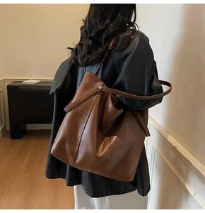 Detail of dark brown tote bag with wrinkled leather texture and slim shoulder strap