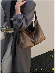 Detail view of the deep brown tote bag showing textured retro leather and buckle side strap