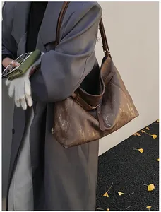 Detail shot of a dark brown tote bag with metallic texture, worn over a grey winter coat
