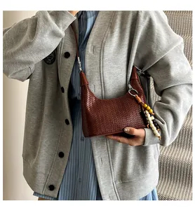 Detail of woven texture hobo bag in dark brown with ethnic wood bead tassel charm
