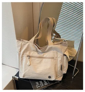 Detail of beige tote bag showing front zipper pocket and durable webbing handles