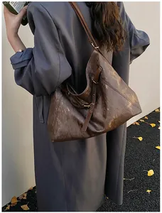 Deep brown tote bag with metallic texture shown as a stylish oversized shoulder bag