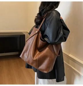 Detail of a large brown textured leather tote bag showing sturdy reinforced rivets and straps