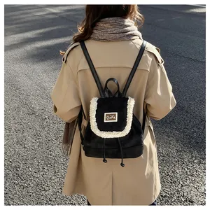 Detail of mini black backpack with white plush trim and embroidered bear patch label