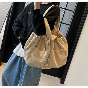 Détail du sac cabas beige en velours côtelé avec texture et cordon de serrage sur modèle
