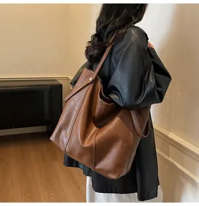 Detail view of the large brown tote bag showing leather texture and fine stitching