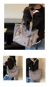 Detail view of a grey nylon tote bag showing zipper pocket and utility side flap pocket