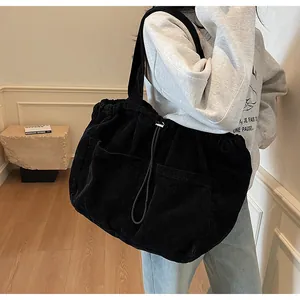 Détail du sac cabas en velours côtelé noir montrant la texture et les poches avant
