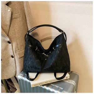 Black textured tote bag with metal buckle detail shown in a stylish travel business setting