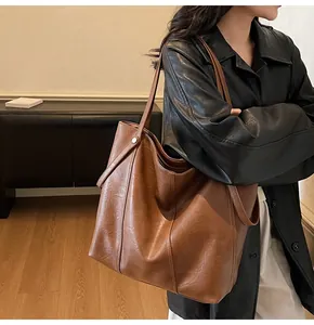 Close-up of caramel faux leather tote bag showing soft texture and metal stud detail