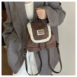 Detail of a brown canvas mini backpack featuring white faux shearling trim and bear patch
