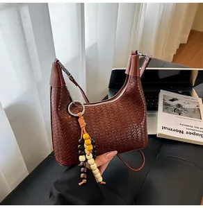 Close-up of woven texture handbag with colorful wooden bead charm in a lifestyle setting