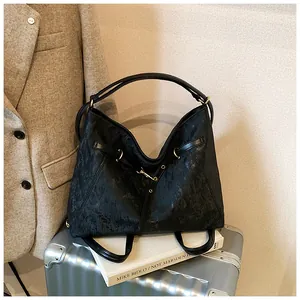 Detail of black vintage leather tote bag with gold metal buckle on a silver suitcase