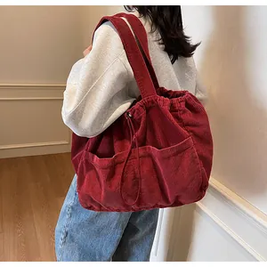 Détail du sac fourre-tout en velours rouge avec grandes poches frontales et cordon de serrage