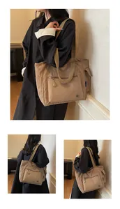 Detail view of khaki nylon tote bag featuring front zip pocket and side compartments