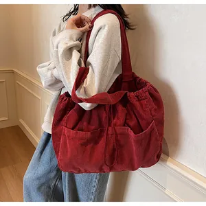 Détail du sac fourre-tout en velours côtelé rouge avec trois poches et cordon