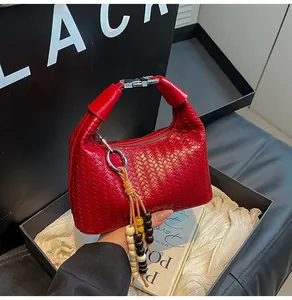 Detail of red woven handbag featuring metallic buckle and colorful bead tassel charm