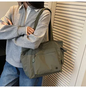 Detail view of the large green commuter tote bag showing spacious zippered front pocket