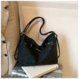 Close-up of textured black leather tote bag with gold hardware on silver suitcase