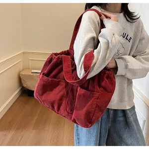 Détail du sac cabas en velours côtelé rouge montrant la texture côtelée et le cordon de serrage