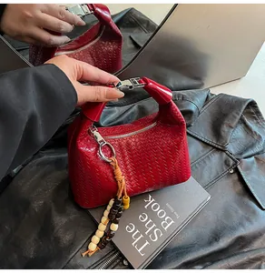 Detail of red woven handbag featuring silver metal handle and bohemian beaded pendant