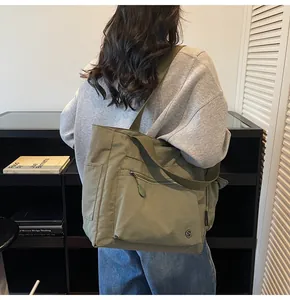 Detail of olive green canvas tote bag showing side pockets and wide fabric shoulder strap