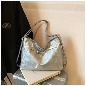 Detailed shot of silver textured tote bag with golden hardware on a suitcase