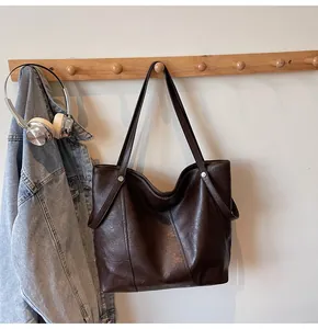 Detail of dark brown tote bag with metallic studs hanging in a casual lifestyle setting