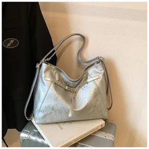 Detail of silver tote bag with brushed metallic texture and gold buckle adjustment