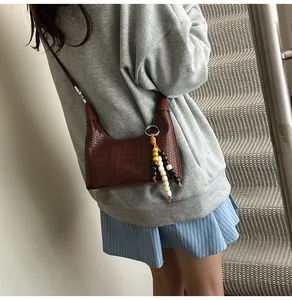 Detailed shot of dark brown woven leather hobo bag with colorful wooden bead tassels