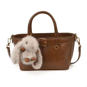 Détail du sac à main en cuir marron avec boucle décorative et breloque lapin en peluche