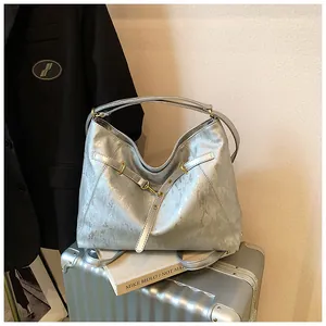 Detail of silver metallic tote bag with gold buckle on a stylish travel suitcase
