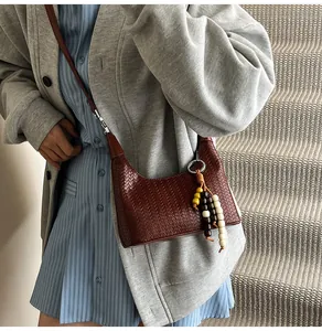 Detail of woven texture on caramel hobo bag with colorful wooden bead tassel accessory