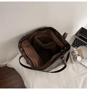 Macro detail of the dark brown tote bag showing striped lining and interior zip pocket