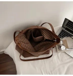 Interior detail of large brown tote bag with striped lining and secure zip pocket