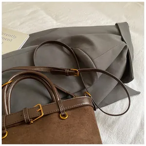 Détail du sac seau marron mat montrant des boucles dorées vintage et des coutures fines