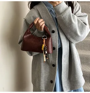 Macro detail of dark brown woven leather texture on hobo bag with wooden bead charm