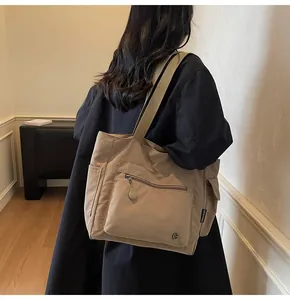 Detailed side view of khaki multi-pocket canvas tote bag worn on shoulder by a model