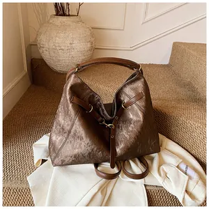 Detailed macro shot of vintage bronze textured tote bag with dark brown leather straps