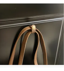 Macro detail of brown pebble grain leather tote with polished gold metallic round hardware