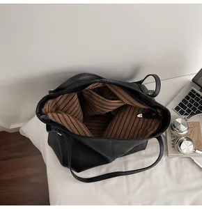 Top-view of large black leather tote bag showing striped lining and spacious interior