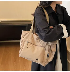 Detail of khaki tote bag showing zippered front pocket and side utility flap pocket
