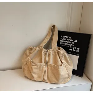 Détail du sac cabas en velours côtelé beige avec deux grandes poches avant et cordon