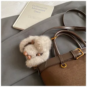 Détail du sac seau marron vintage avec breloque en peluche et boucles dorées sur livre