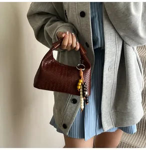 Close-up of dark brown woven leather handbag with colorful wooden bead tassel charm