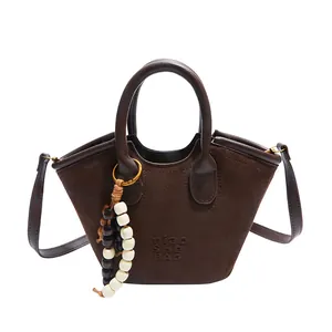 Brown suede tote bag with leather handles and decorative beaded tassel charm