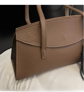 Close-up of brown lychee grain leather handbag featuring flap closure and neat stitching