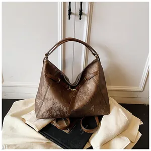 Detail of vintage brown tote bag texture with metallic finish and gold hardware buckles