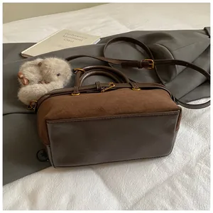 Détail du sac vintage montrant le daim marron et le cuir lisse avec pendentif en peluche