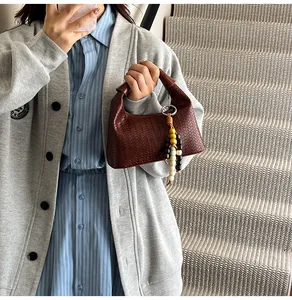 Detailed texture of dark brown woven leather handbag with colorful wooden bead charm